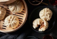 Steamed buns next to steamer full of buns